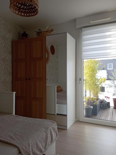 1 dormitorio con 1 cama y puerta corredera de cristal en Chambre nature chez l'habitant, en Estrasburgo