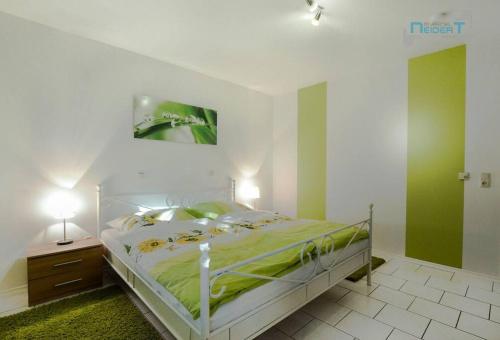 a bedroom with a bed with green sheets and a painting at Ferienwohnung Tor zum Spessart in Wächtersbach