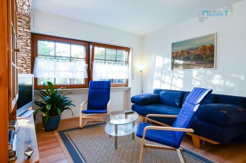a living room with a blue couch and two chairs at Ferienwohnung Tor zum Spessart in Wächtersbach