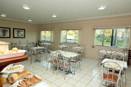 - une salle à manger avec des tables, des chaises et des fenêtres dans l'établissement Candeias Hotel, à Batatais