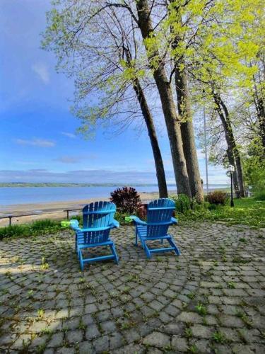 two blue chairs sitting on a stone patio near the water at PANORAMA DE LA DETENTE-BORDURE DE FLEUVE (309418) in Saint-Laurent-de-l'ile d'Orleans