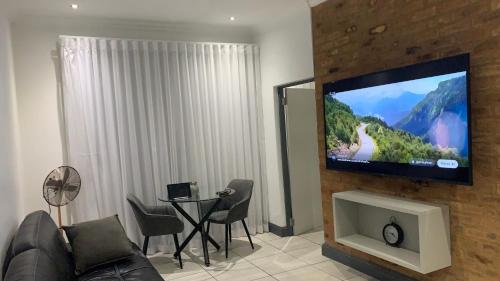 a living room with a couch and a tv on a wall at CALDESMO - Upmarket Apartment in Pretoria