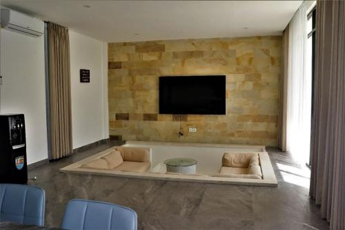sala de estar con TV en una pared de piedra en Merryland Villa Bali en Jimbaran