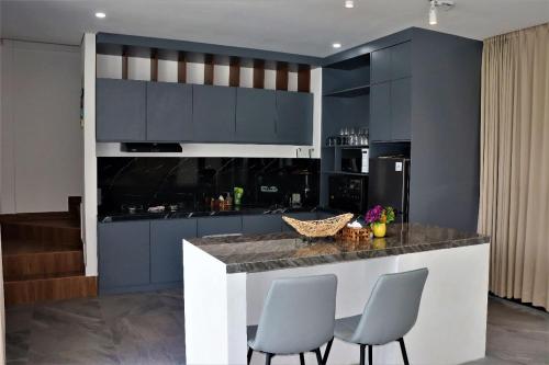 una cocina con armarios azules y una barra con sillas en Merryland Villa Bali en Jimbaran