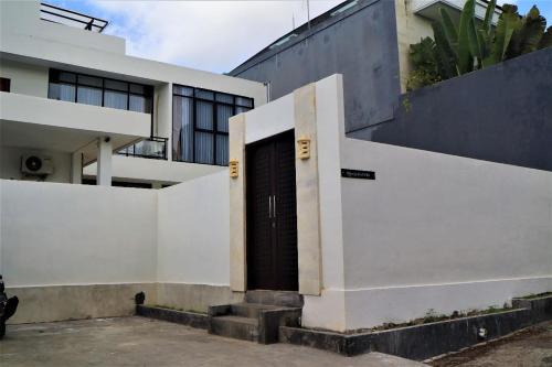 un edificio blanco con una puerta negra. en Merryland Villa Bali, en Jimbaran