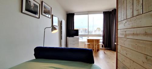a bedroom with a couch and a desk with a window at Le loft-boat in Deauville