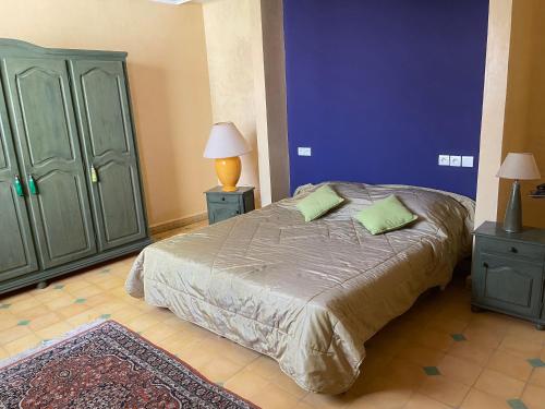 a bedroom with a bed with two green cabinets at Ker Roz in Tamraght Ouzdar