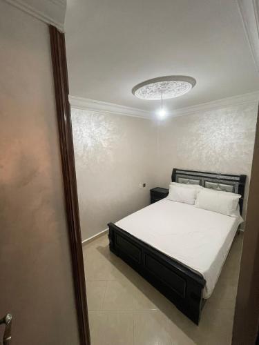 a bedroom with a bed with white sheets and a chandelier at Fully equipped ground floor apartment in Safi