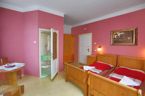 two beds in a room with pink walls at Pension Harmonie in Hrubá Skála