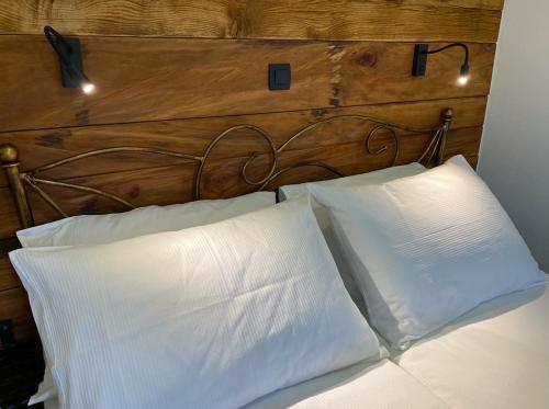 1 cama con 2 almohadas blancas y cabecero de madera en Spacious apartment in nature with infrared sauna! en Postojna