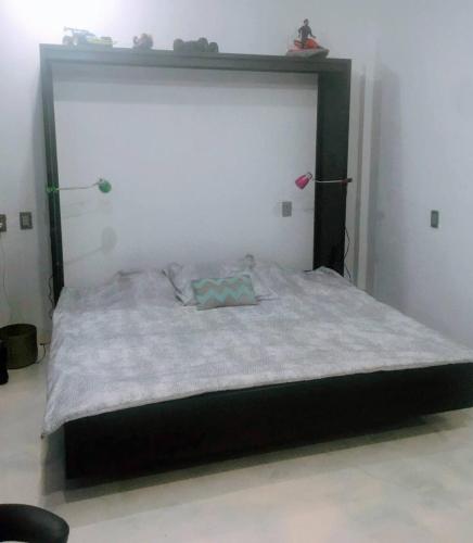 a bed with a black frame in a room at Loft en Tercer Piso con Vista Panoramica in Puebla
