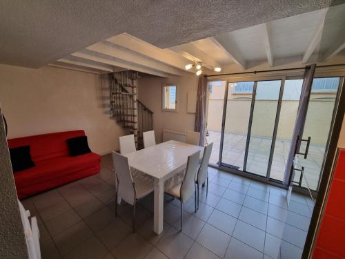 - un salon avec une table, des chaises et un canapé rouge dans l'établissement Cap d'Agde-Richelieu-Résidence Delphéapolis, au Cap d'Agde