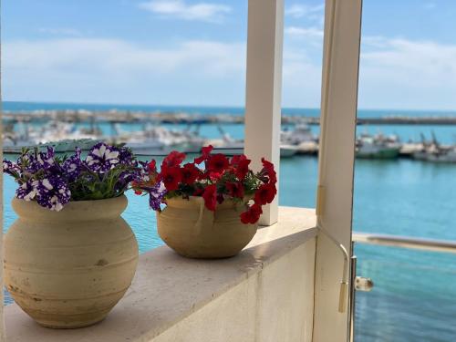 dois vasos com flores sentados numa saliência perto da água em Casa Marina em Sciacca