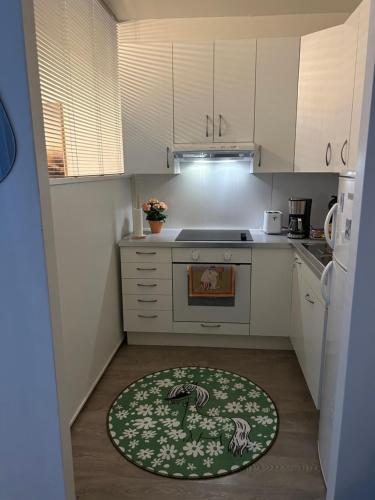 a kitchen with white cabinets and a rug on the floor at Studio in Rovaniemi