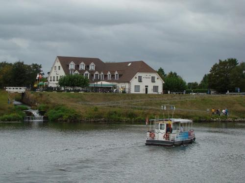 a boat traveling down a river in front of a house at Hotel De Spaenjerd in Kinrooi