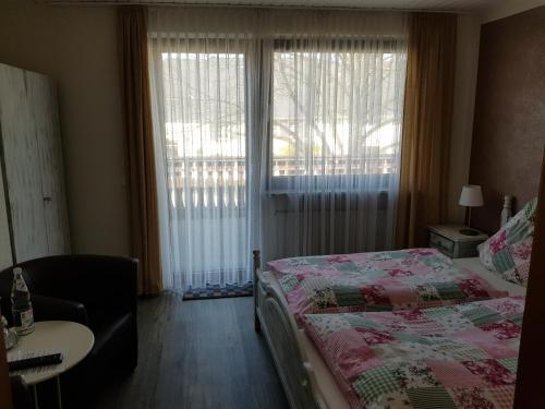 a bedroom with a bed and a chair and a window at Gästehaus Vinum Doppelzimmer in Leiwen