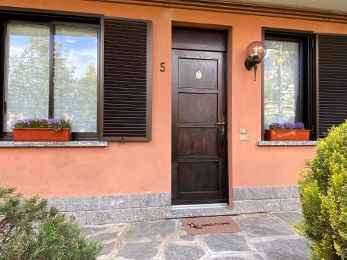 una casa con una puerta marrón y dos ventanas en Appartamento “La casetta di Mirto”, en Porlezza