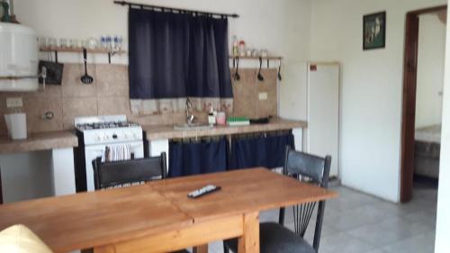 cocina con mesa de madera con sillas y barra en turismo chascomus en Chascomús
