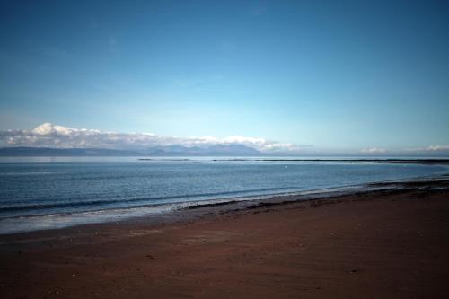 a beach with the ocean and mountains in the background at Grand top floor apartment in the Royal Bank House in Maybole