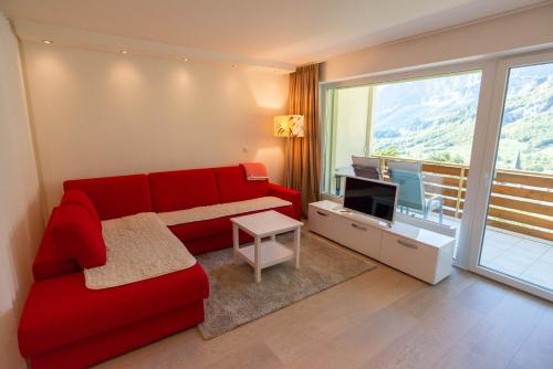 a living room with a red couch and a television at Haus Cristal - 1441m in Leukerbad