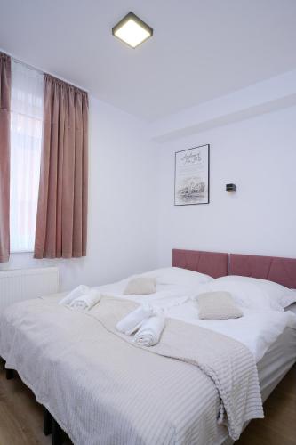 a bedroom with two beds with white sheets and a window at Apartmani NAN in Visoko