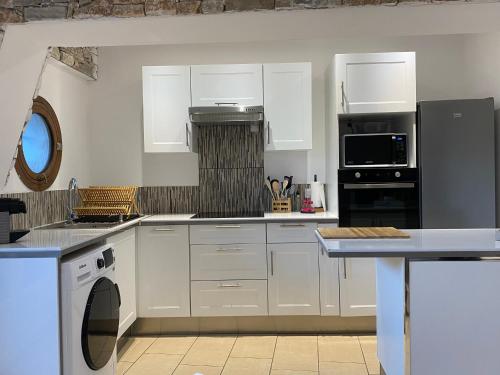 a kitchen with white cabinets and a black refrigerator at Magnifique T2 en bord de mer in Le Lavandou