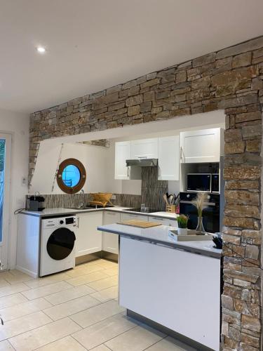 a kitchen with white cabinets and a stone wall at Magnifique T2 en bord de mer in Le Lavandou