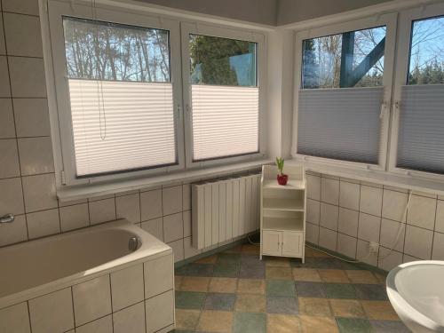 a bathroom with three windows and a tub and a sink at Ferienhaus mit Terrasse in der Uckermark in Milmersdorf