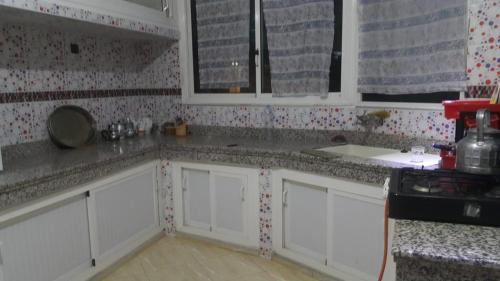 eine Küche mit weißen Schränken und Granitarbeitsflächen in der Unterkunft Appart el bassatine pr famille in Meknès