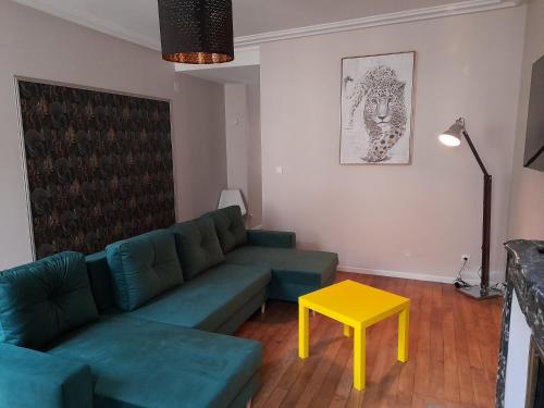 a living room with a green couch and a yellow table at Appartement Atypique in Sedan
