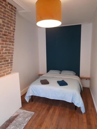 a bedroom with a white bed and a brick wall at Appartement Atypique in Sedan