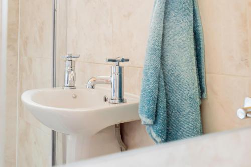 a bathroom with a sink and a blue towel at Shirley House 4, Guest House, Fully Equipped Kitchen with Fridge, Washer, Dryer, Self Catering, Self Check in, Great for Contractors, 5 min to BAT, 20 min to Fawley Refinery, close to Southampton Central, Ideal for Longer Stays in Southampton
