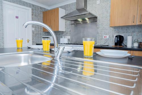 una cocina con 2 vasos de zumo de naranja en una barra en Shirley House 4, Guest House, Self Catering, Self Check in with smart locks, use of Fully Equipped Kitchen, close to City Centre, Ideal for Longer Stays, Excellent Transport Links en Southampton