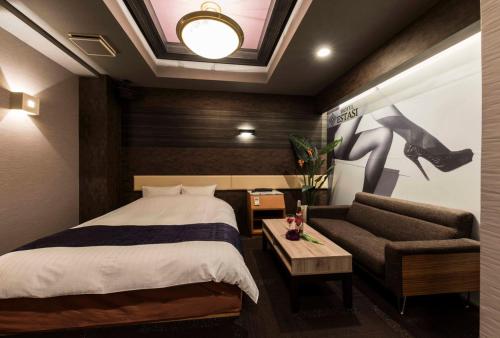 a hotel room with a bed and a couch at HOTEL ESTASI Adult only in Wakayama