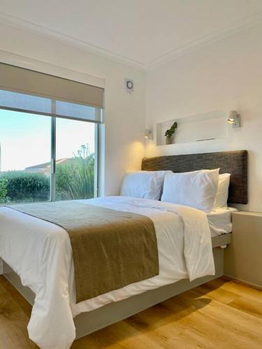 a bedroom with a large bed with a large window at Hermanus Sea Breeze in Hermanus