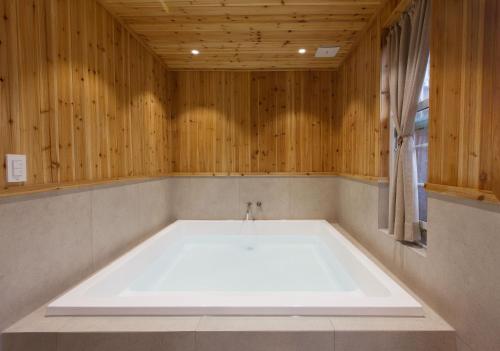 uma grande banheira num quarto com paredes de madeira em Jeonju Hanok Little Prince em Jeonju