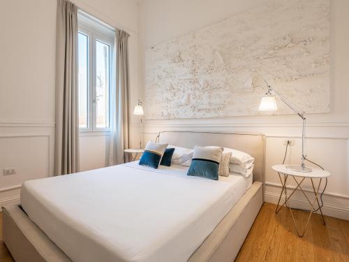 una camera da letto con un grande letto bianco con cuscini blu di PLEY Boutique Del Centro a Cagliari