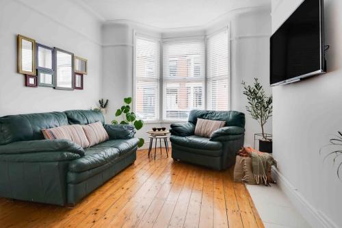 uma sala de estar com dois sofás verdes e uma televisão em Orange Rentals - In my 4 bedroom Liverpool Home em Liverpool