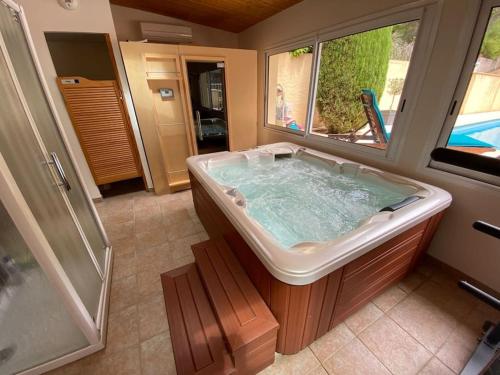 W łazience z oknem znajduje się duża wanna. w obiekcie Maison de famille (piscine, jacuzzi et sauna) w mieście Quillan