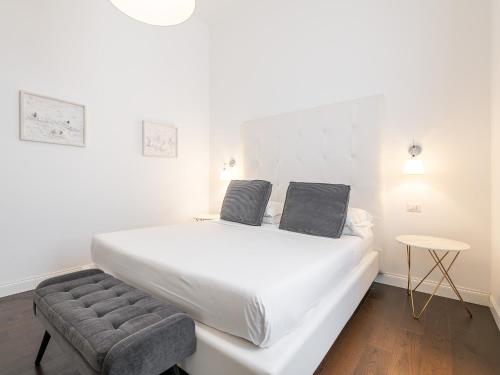 a white bed with two pillows and a chair in a room at PLEY Cagliari Boutique Suites in Cagliari
