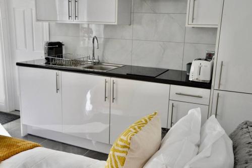 uma cozinha branca com um lavatório e um balcão em The White House Retreat em Londres