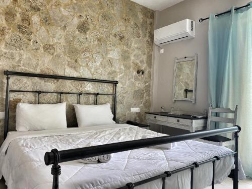 - une chambre avec un lit et un mur en pierre dans l'établissement Hotel Kastri, à Loutra Edipsou