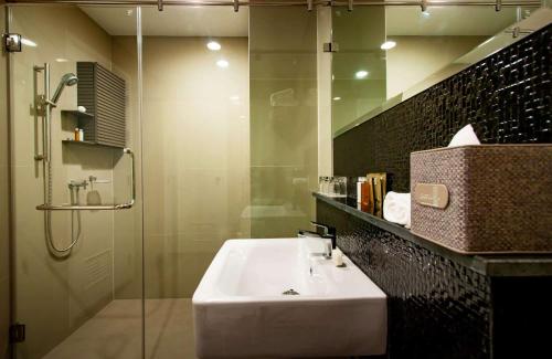 a bathroom with a sink and a glass shower at Brique Suite in Chiang Mai