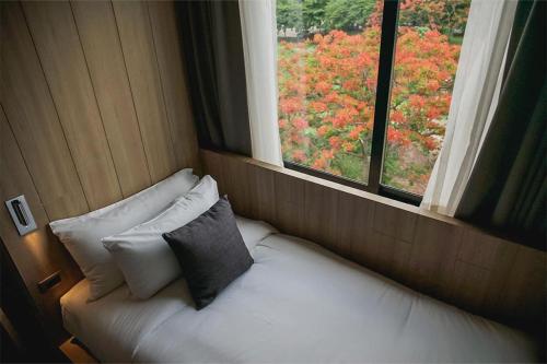 a white bed with pillows in a room with a window at Brique Suite in Chiang Mai