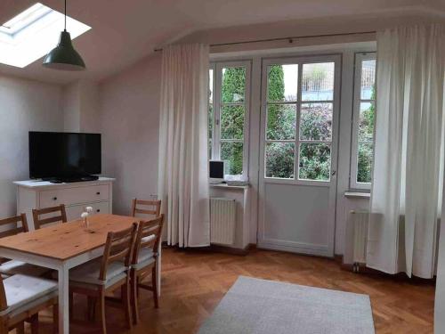 uma sala de jantar com uma mesa, uma televisão e janelas em Urlaub in der königlichen Villa em Berchtesgaden