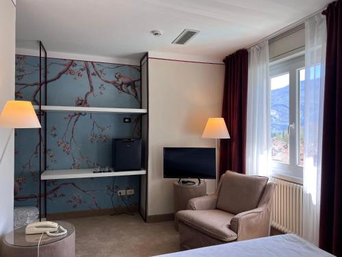 Habitación de hotel con silla y TV en Villa Miravalle, en Riva del Garda