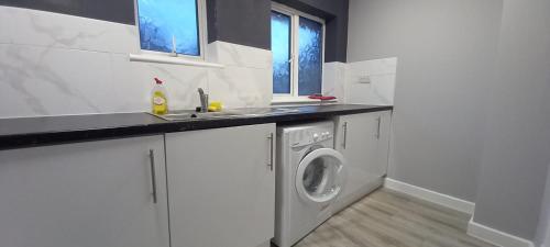 eine Küche mit einer Spüle und einer Waschmaschine in der Unterkunft Stylish Home from Home in Orpington