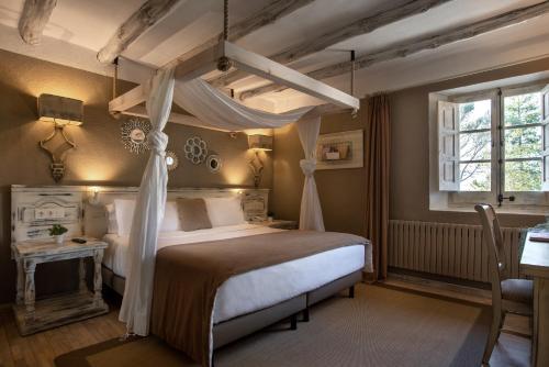 Hotel Luze El Toro في بيرَيوبلانو: غرفة نوم مع سرير المظلة وطاولة