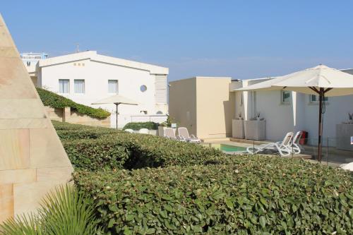 a hedge in front of a house with chairs and an umbrella at Dimore di Mare in Termoli