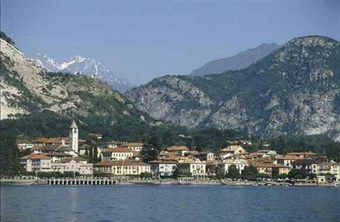 a town on the shore of a body of water with mountains at La Casetta di Baveno in Baveno